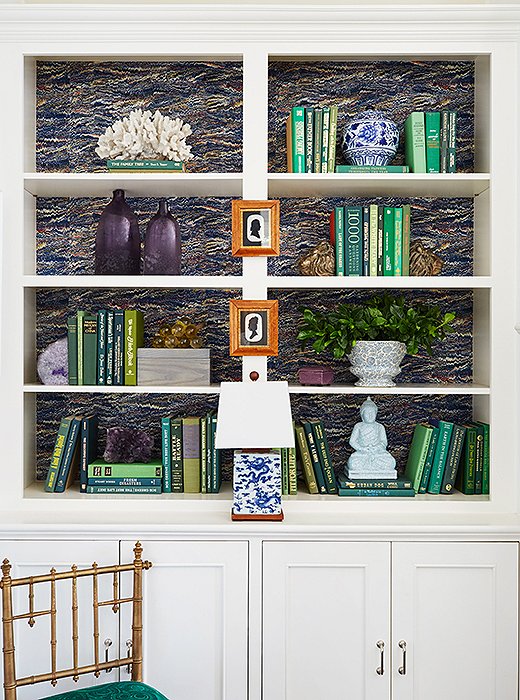 Wallpaper on the back of this bookcase gives cohesion to the various arrangements. Design by Jean Feldman. Photo by Jessica Sample. 
